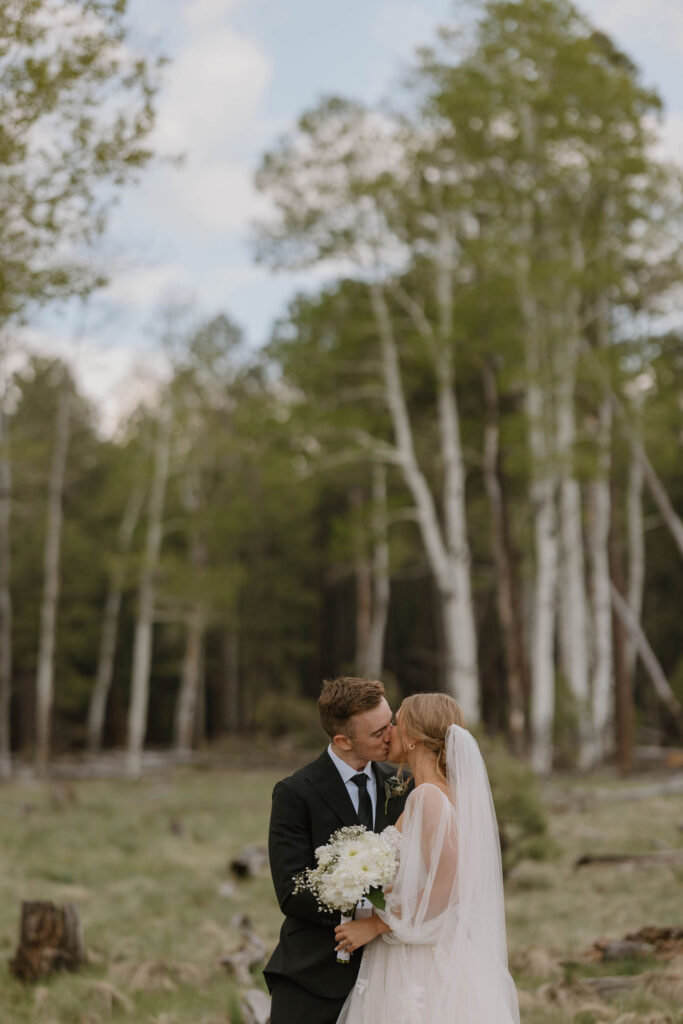 bride and groom kissing during outdoor wedding day at arizona nordic village