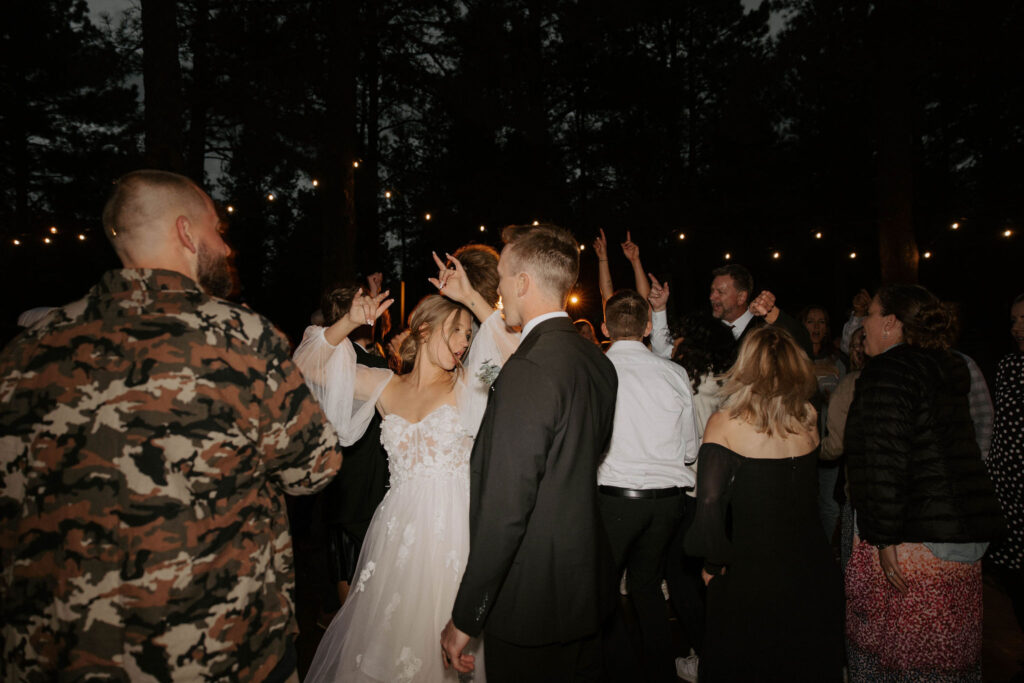 dance party photo in an outdoor forest wedding with bride and groom and family and friends