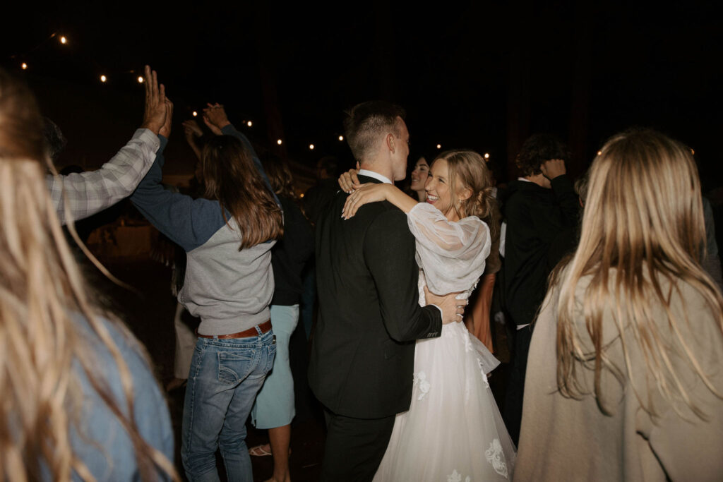 dance party photo in an outdoor forest wedding with bride and groom and family and friends