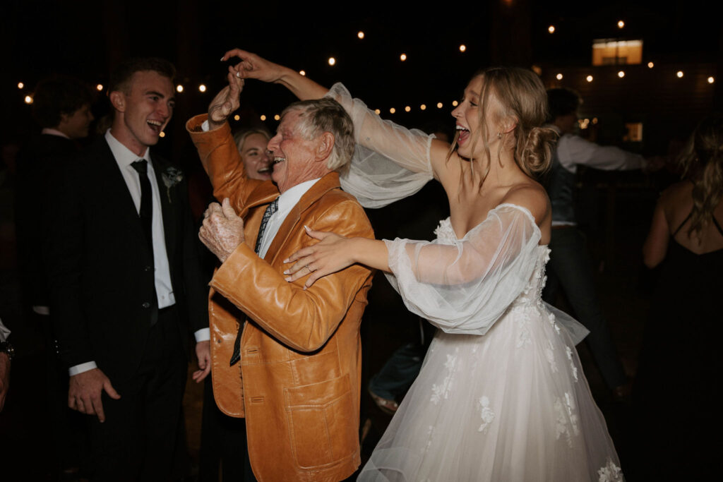 dance party photo in an outdoor forest wedding with bride and groom and family and friends