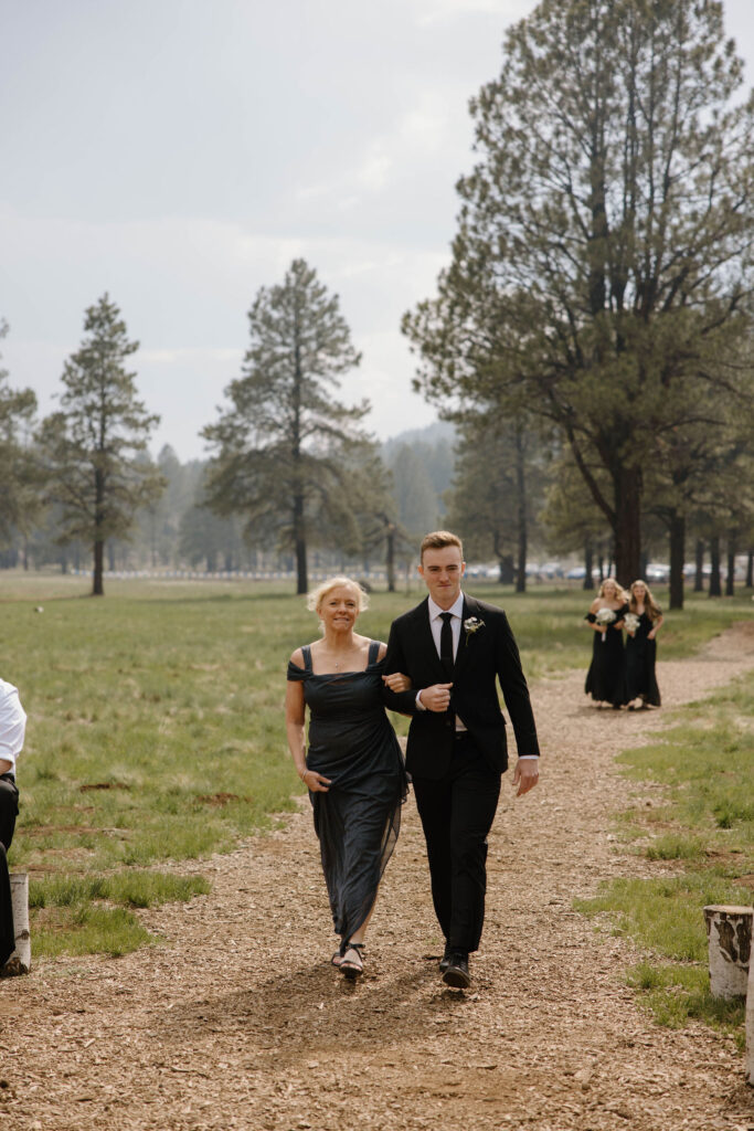 ceremony photo of groom walking with mom during outdoor wedding day at arizona nordic village