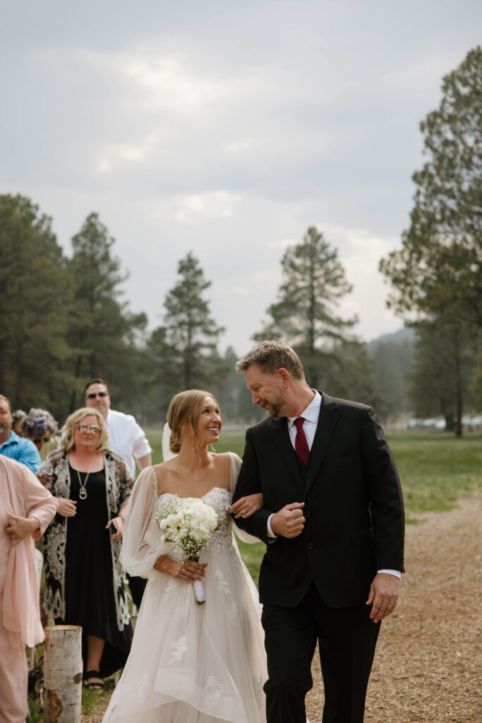 ceremony photo of bride walking with dad during outdoor wedding day at arizona nordic village