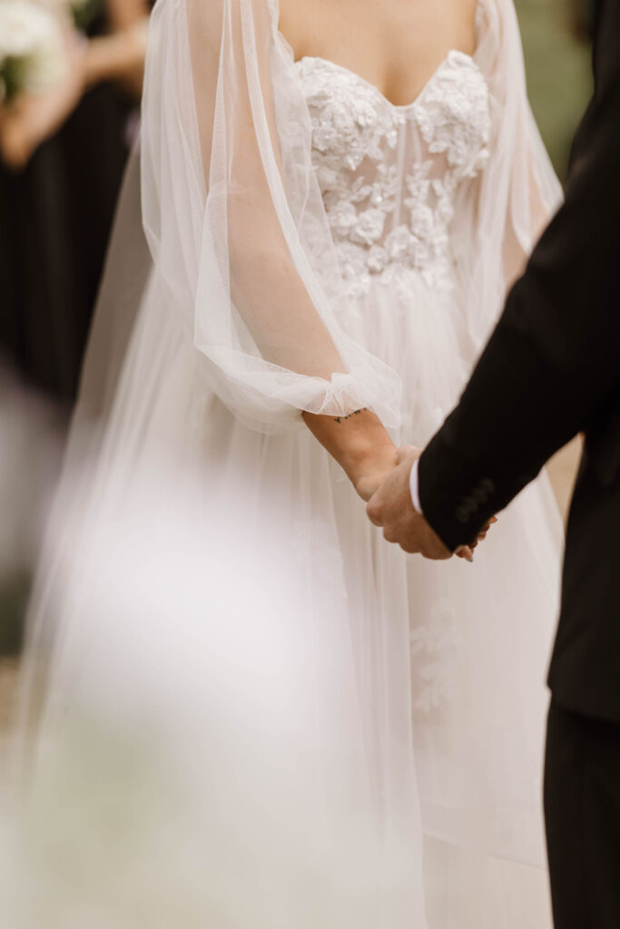 ceremony photo of groom holding hands at arbor with bride during outdoor wedding day at arizona nordic village