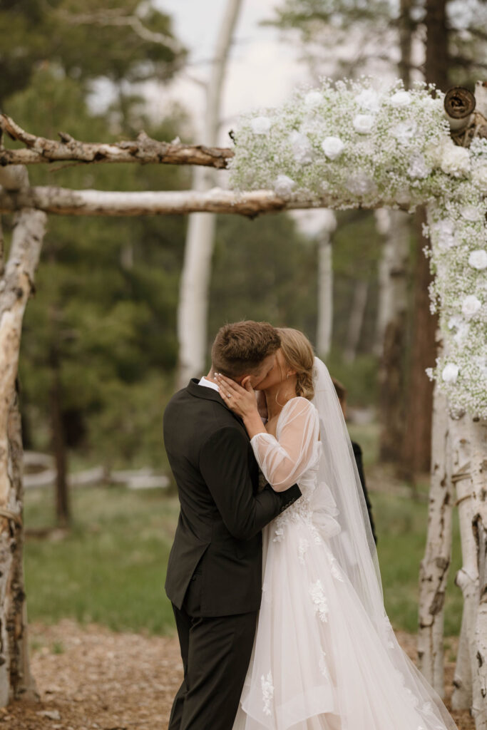 ceremony photo of groom kissing bride during outdoor wedding day at arizona nordic village